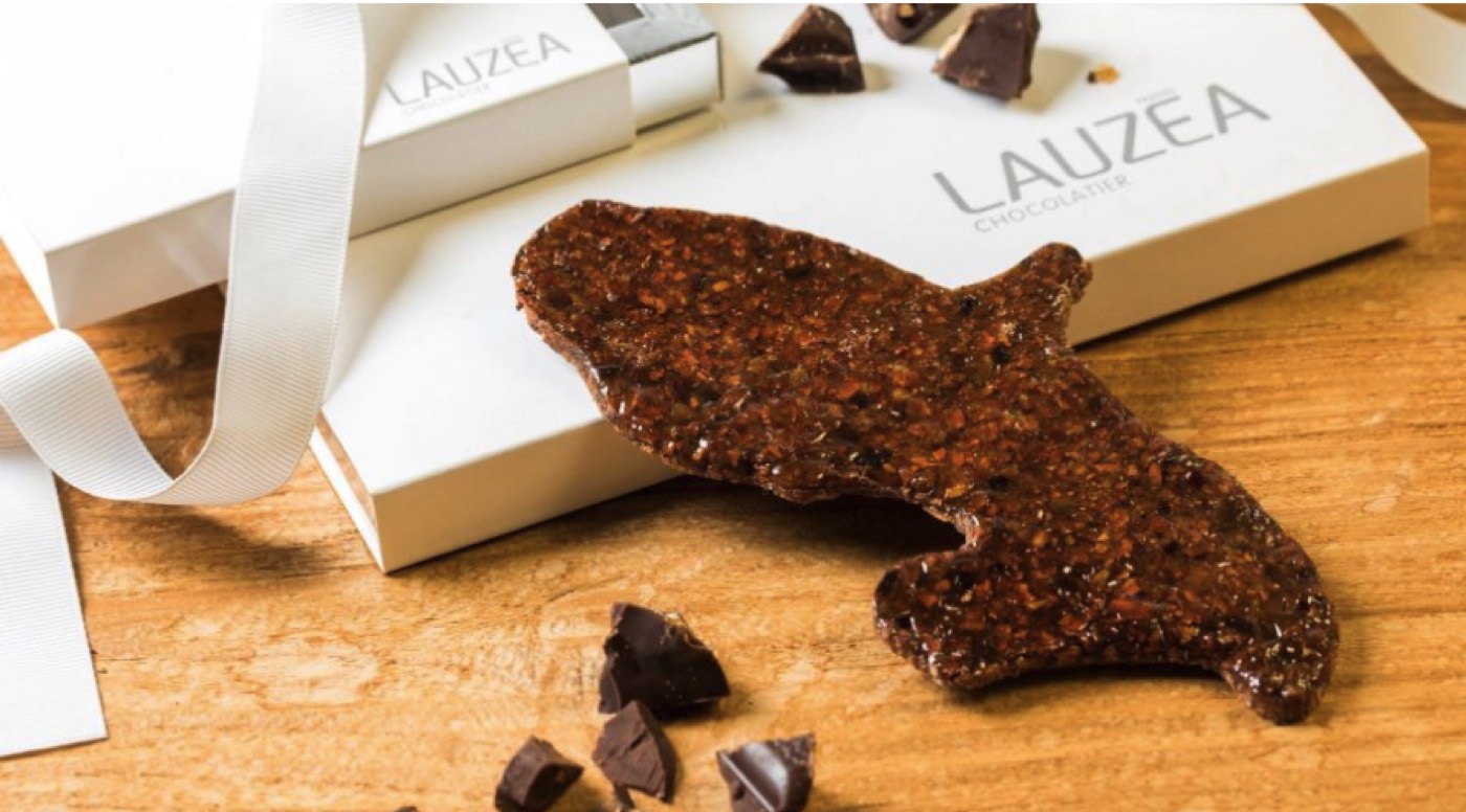 Lauzea Chocolatier gift boxes with a ribbon, beside broken dark chocolate