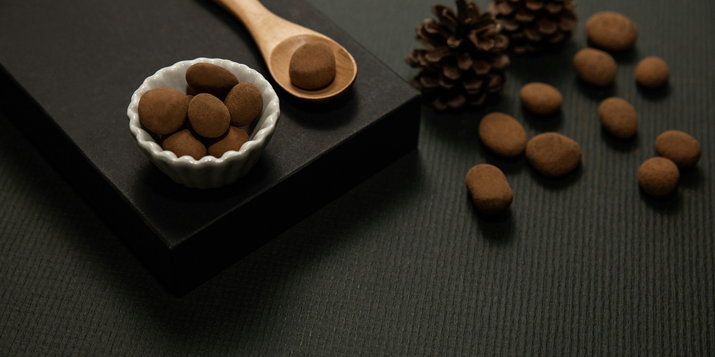 Cocoa-dusted almonds in a fluted dish on a black slate board